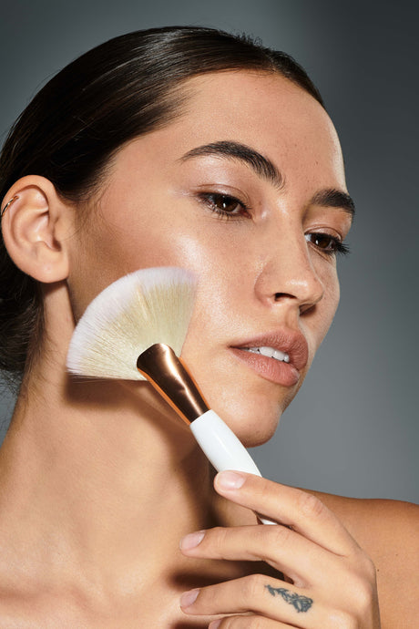 Beauty Shopify Theme Beautify Woman. applying makeup with a brush on a gray background