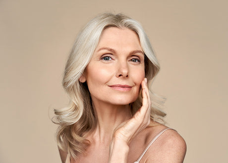 Beauty Shopify Theme Beautify. Woman with gray hair touching her face against a beige background