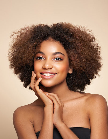 Beauty Shopify Theme Beautify. Woman with curly hair smiling against a beige background