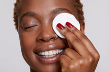 Beauty Shopify theme Beautify. Woman holding a makeup pad over her eye with a neutral background.