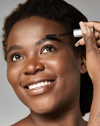 Beauty Shopify theme Beautify. Woman using an eyebrow enhancer brush with a neutral background.